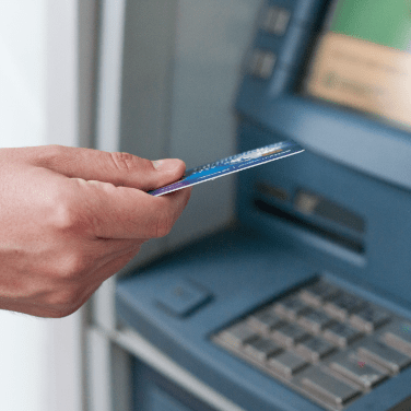 close up of hand holding credit card at ATM