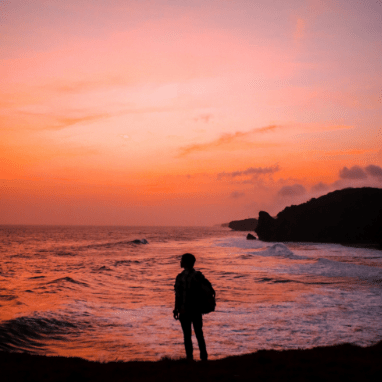 person standing by ocean at sunset